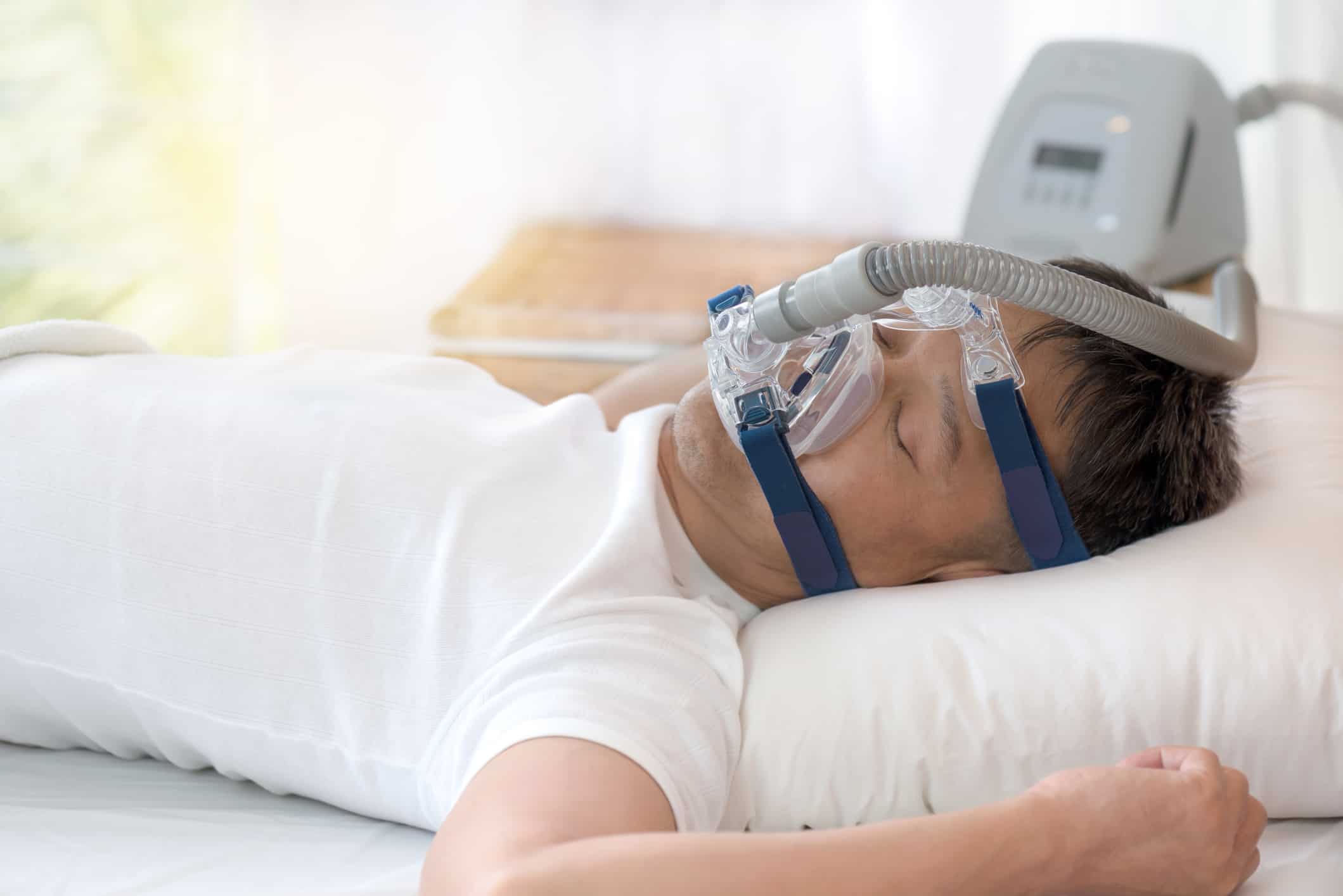 Man sleeping while wearing a CPAP mask for sleep apnoea.