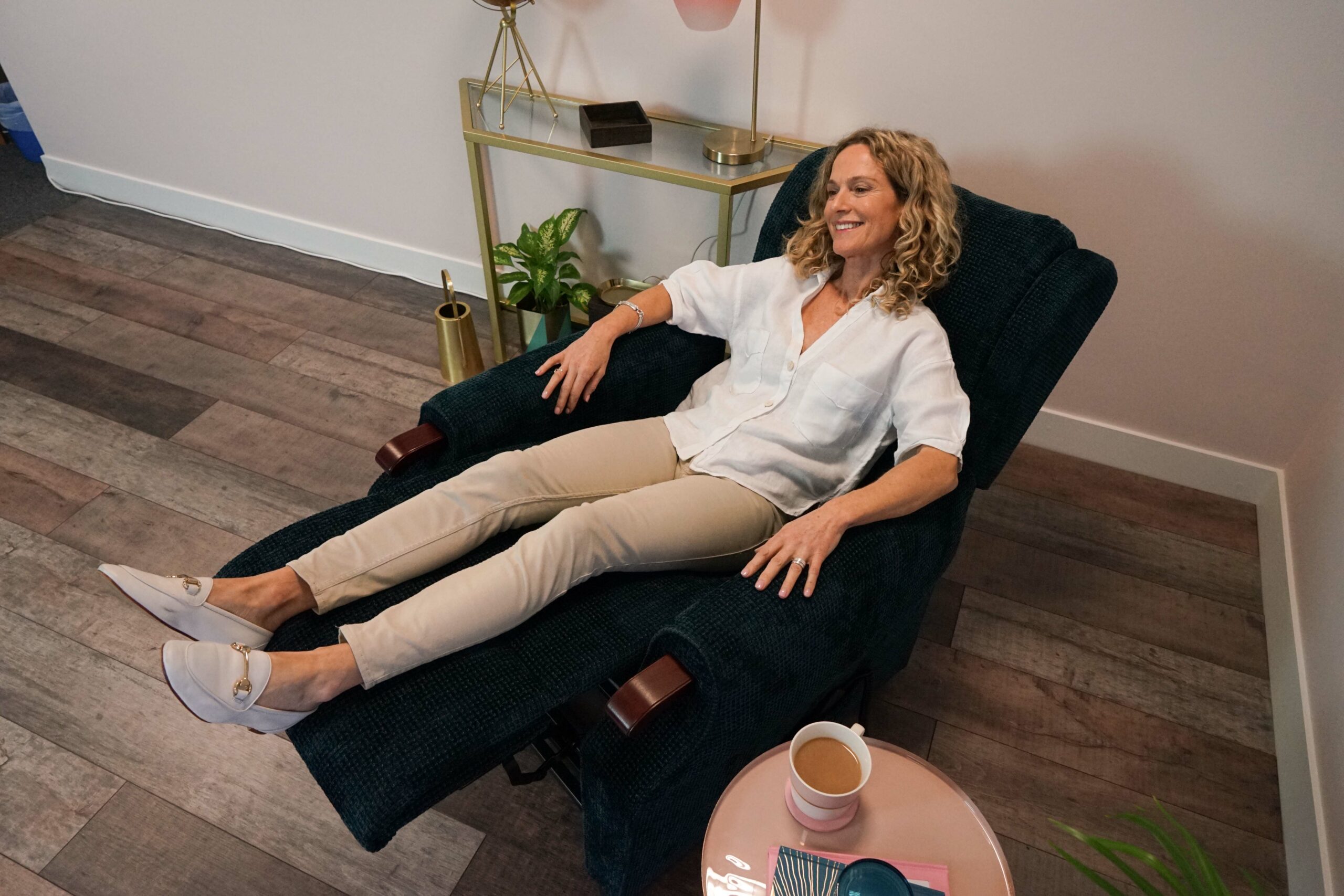 A smiling woman reclining in a riser recliner chair. Read our article to find out are recliner chairs bad for your back?